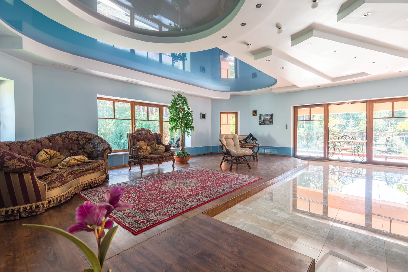 Spacious living room with a curved multi-level painted ceiling and tall windows